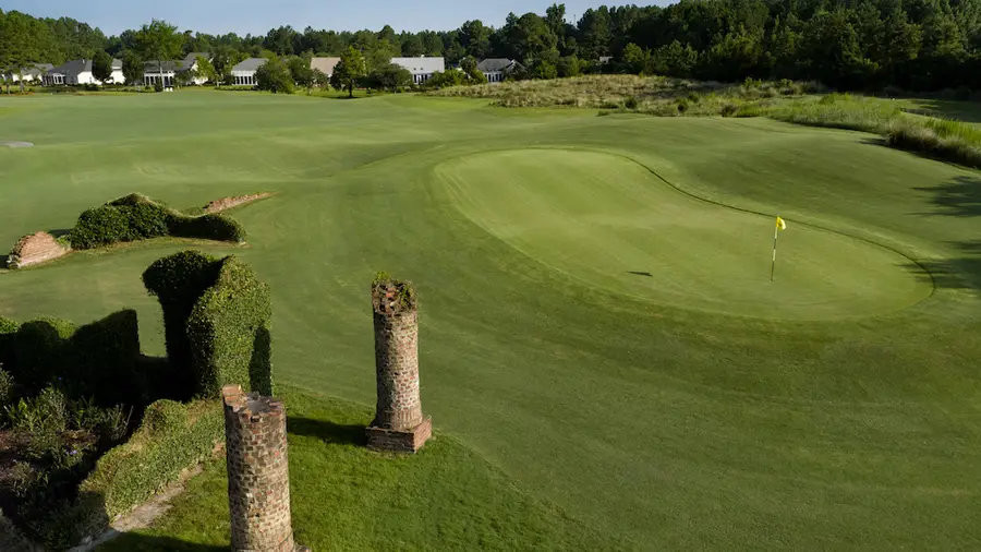 The brick ruins beside a green on the Love Course with villas behind