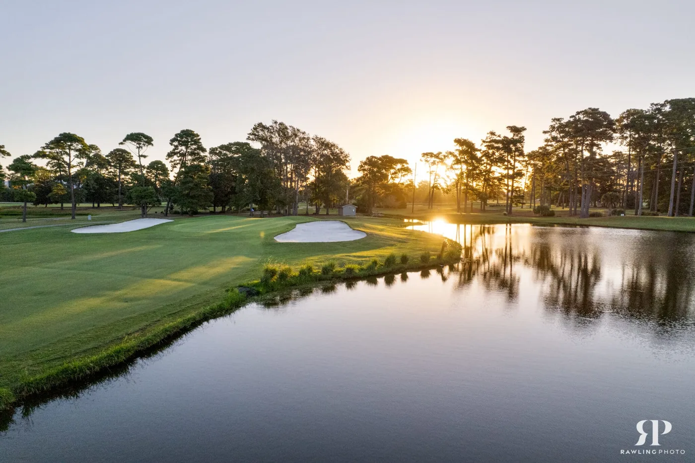 Sunrise over a lake and fairway at Beachwood Golf Club with bunkers guarding the green