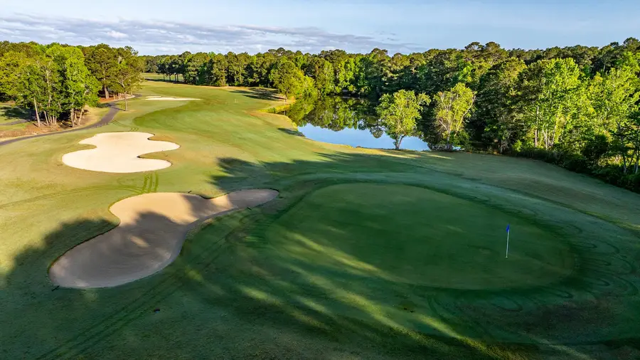 Aerial view of a green at Meadowlands with two bunkers and a lake and treeline behind
