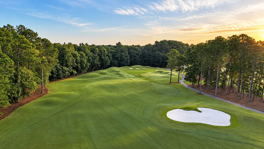 The opening fairway at Wild Wing Avocet from the air at sunset, with a large bunker on the right and pines down both sides