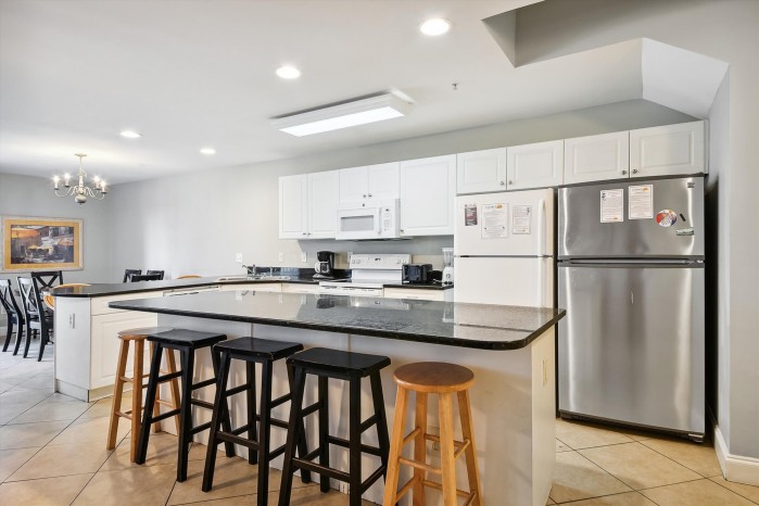 Condo kitchen with a granite island and breakfast bar seating at Ambassador Villas