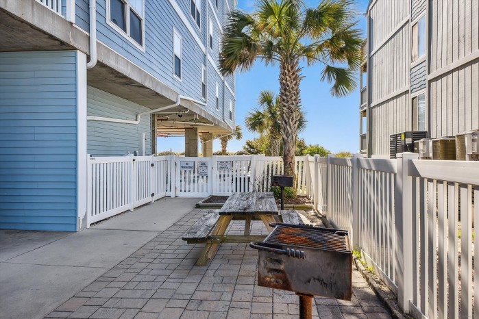 Picnic tables and charcoal grills on the outdoor patio at Ambassador Villas