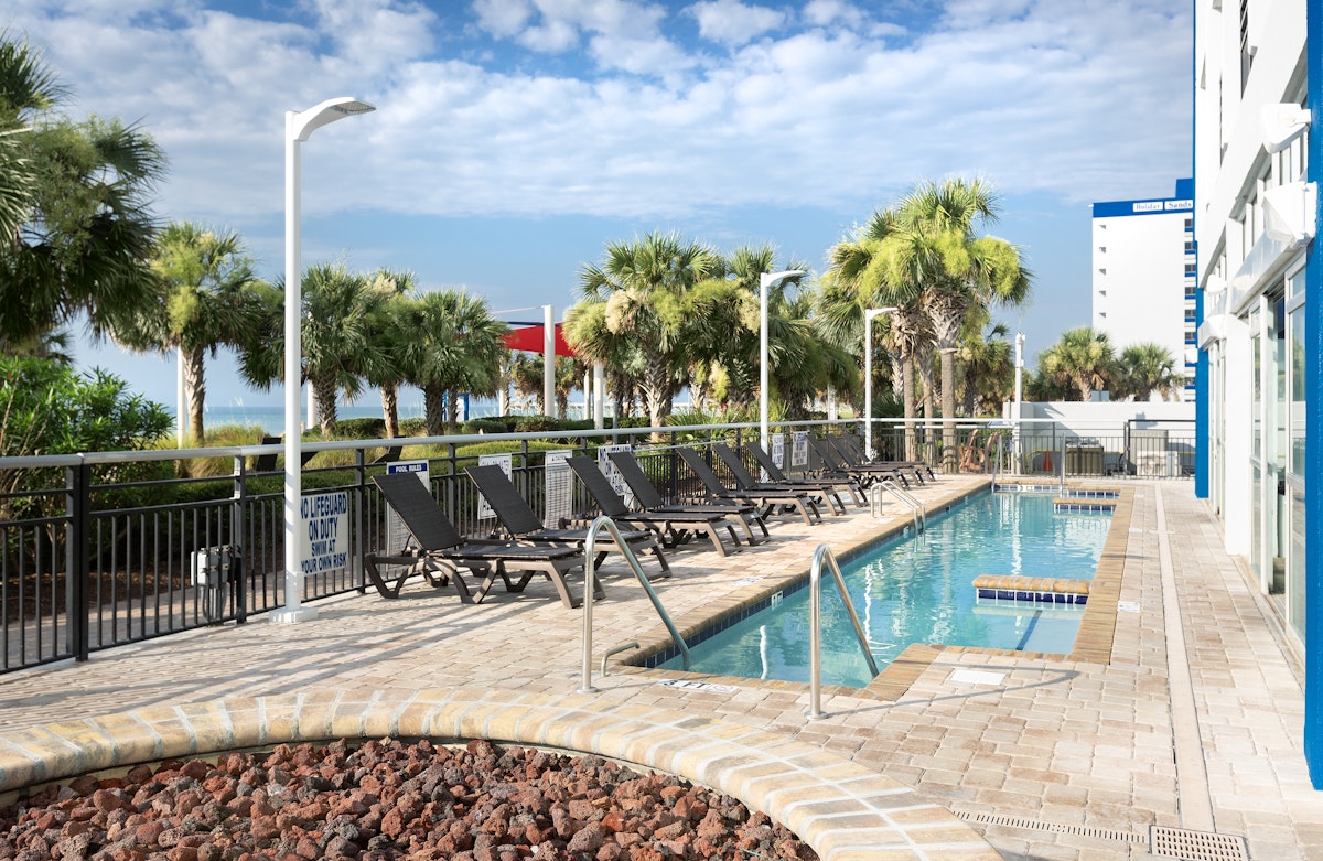 The outdoor pool and sun loungers at Bay View Resort, with the beach beyond the palms