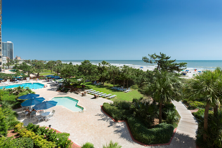 The pools, boardwalk gardens and the ocean beyond at Beach Colony Resort