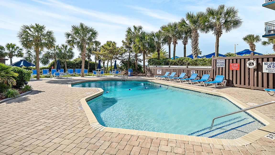 The outdoor pool ringed with palms at Beach Colony Resort