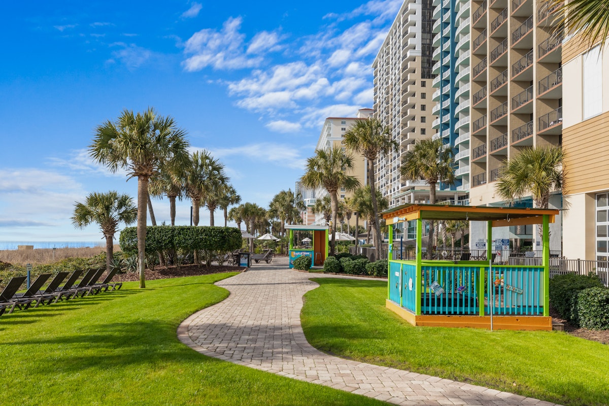 Palms, lawn and sun loungers between the Breakers Resort towers and the beach