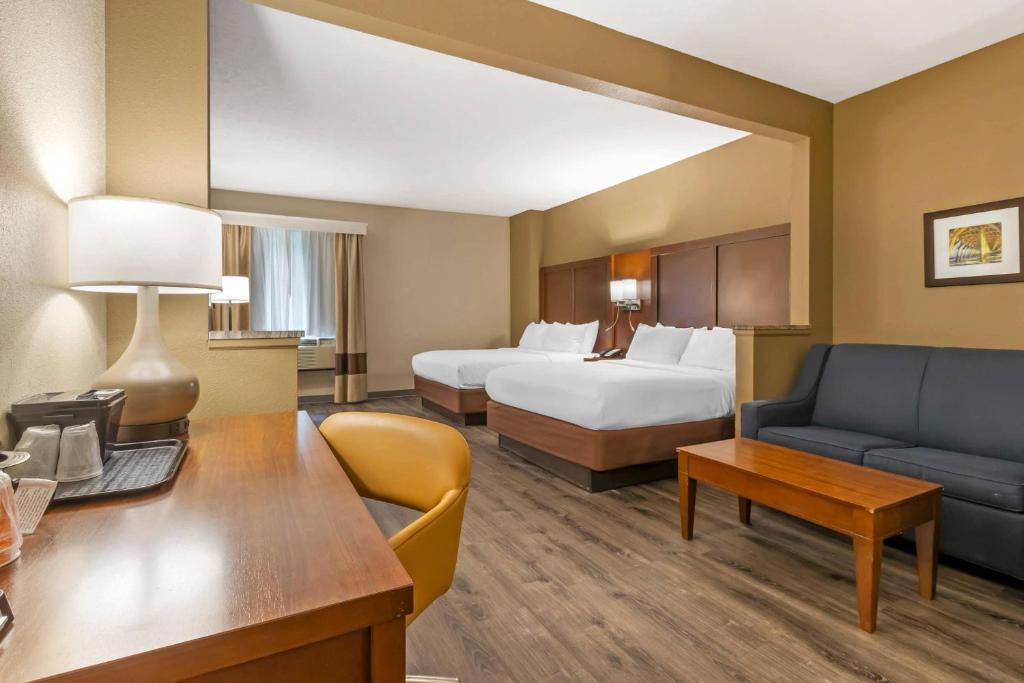 Living area of a suite at Comfort Suites at the University, with a sofa, desk and two queen beds