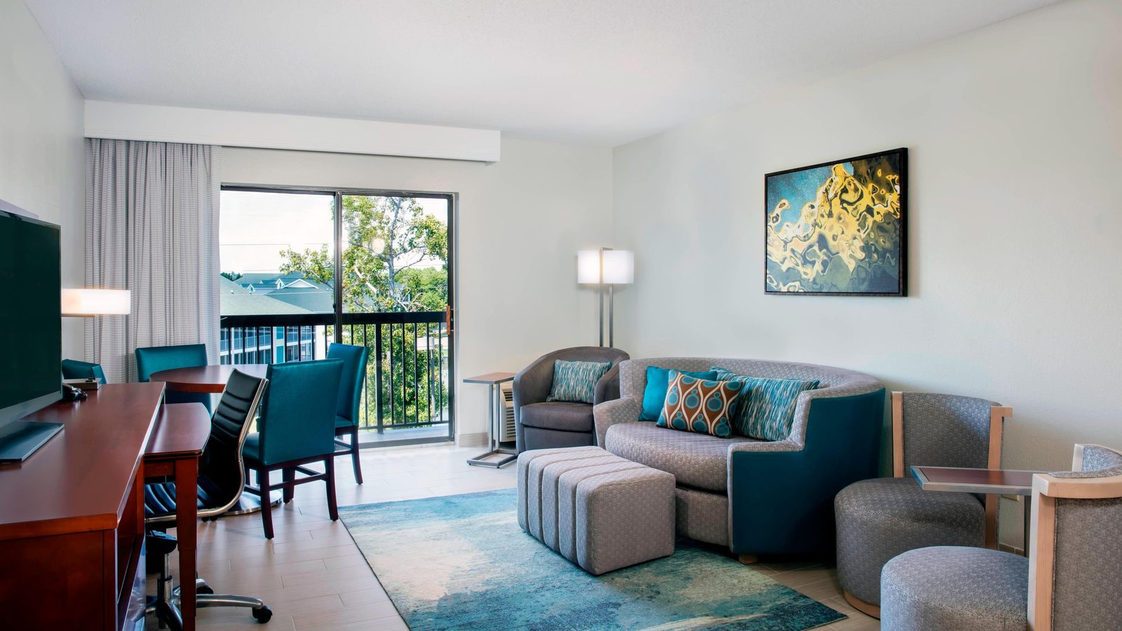 Living area of a suite at the Courtyard by Marriott, with a sofa, dining table and a balcony