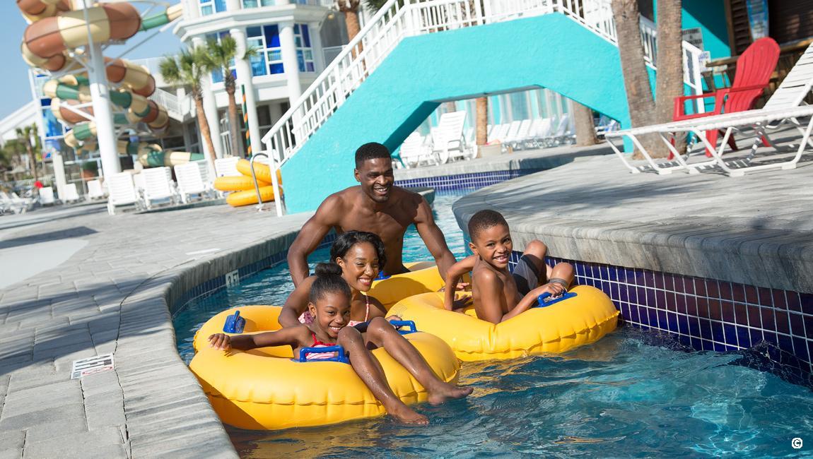 A family floating the outdoor lazy river at Crown Reef Beach Resort