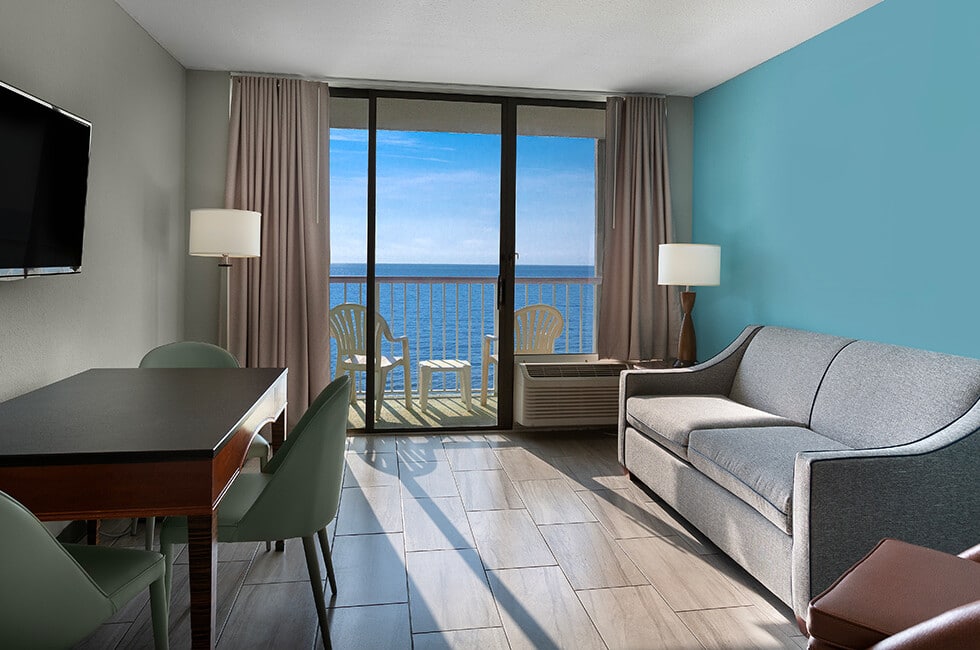 Oceanfront suite living room at Crown Reef Beach Resort, with a balcony over the water