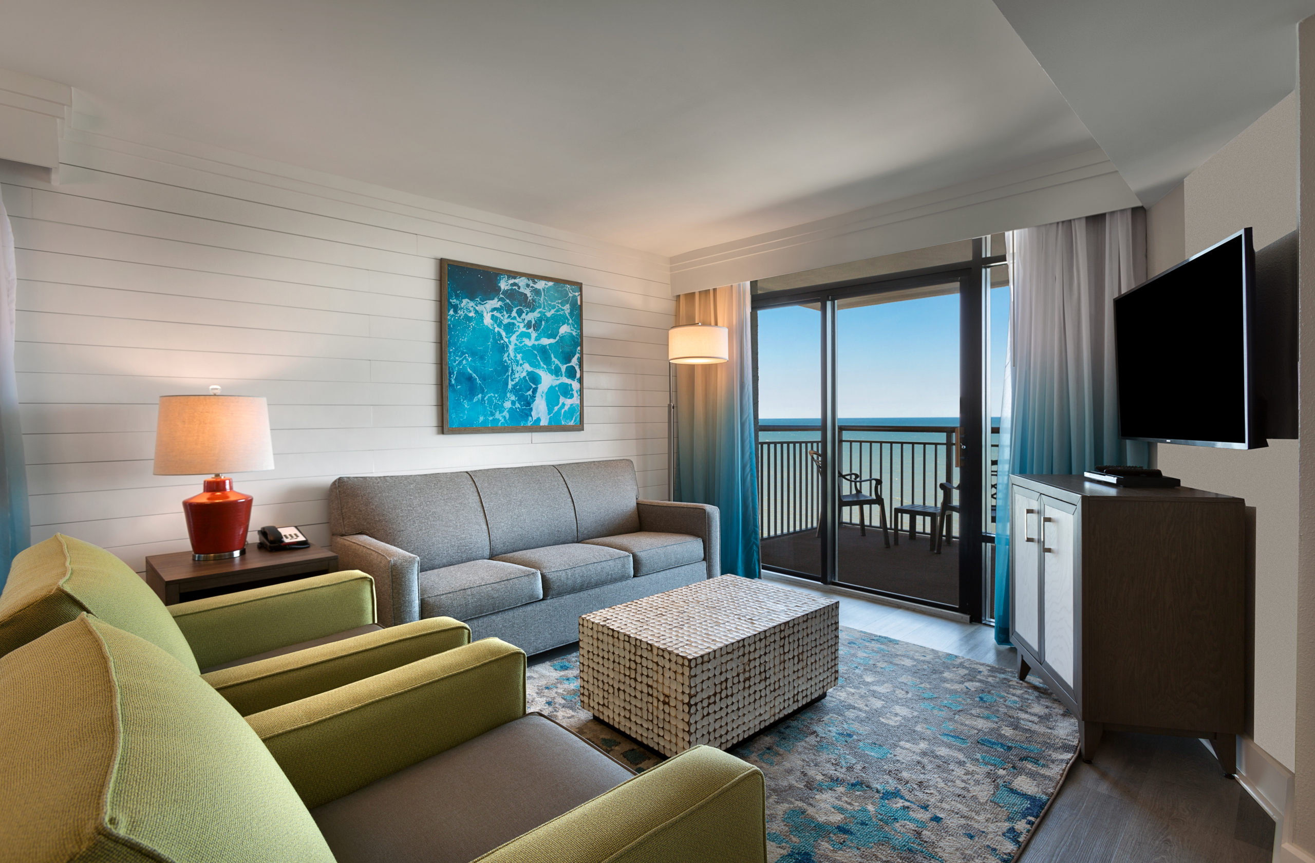 Living area of an oceanfront suite at Grande Cayman Resort, with sliding doors onto the balcony