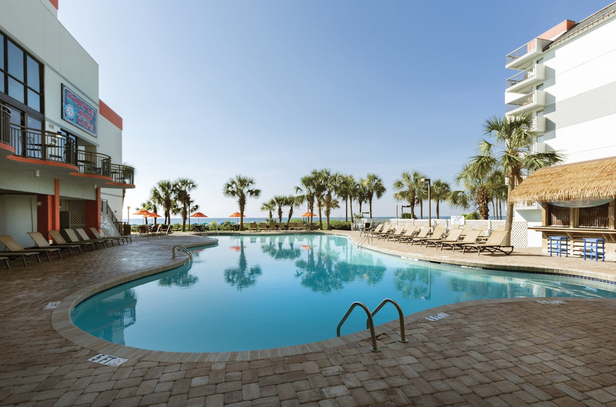 The oceanfront outdoor pool, palms and tiki bar at Grande Cayman Resort