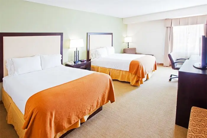 Guest room with two queen beds, a work desk and an armchair by the window