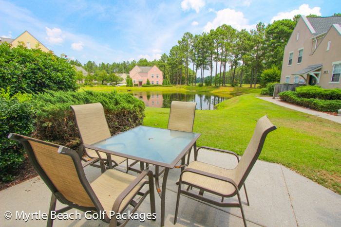 Patio table and chairs outside a villa at Legends, looking across the lawn to the lake