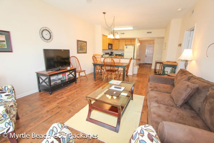 Open living area and kitchen inside a villa at Legends, with a dining table beyond