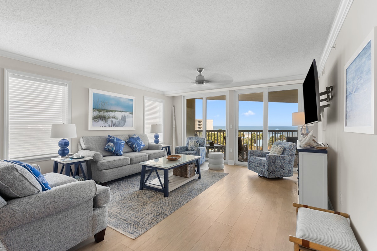 Living area of a condo at Litchfield Beach and Golf Resort, looking out to the balcony and the water