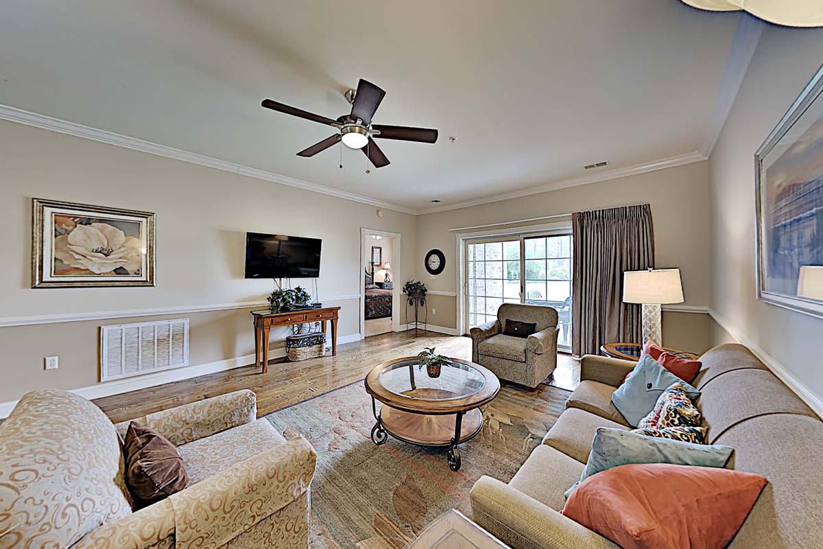 Living area of a villa at Myrtlewood, with sofas, an armchair and doors onto the balcony