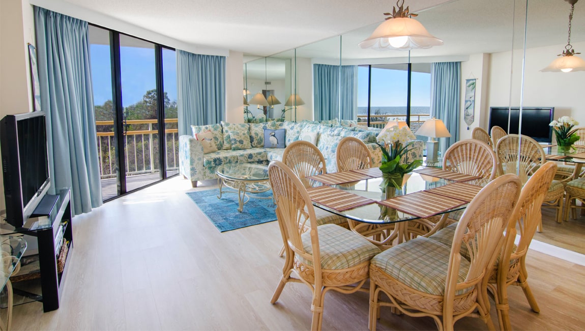 Open living and dining area of a villa at Ocean Creek Resort, with the ocean through the balcony doors