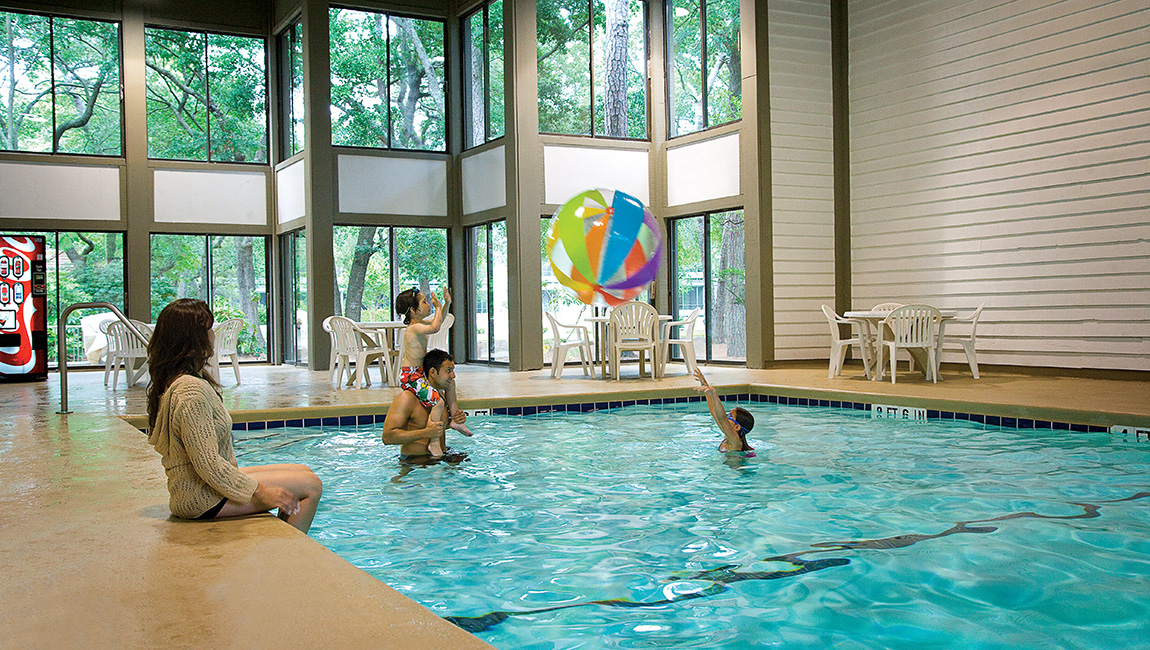 The indoor pool under tall windows at Ocean Creek Resort
