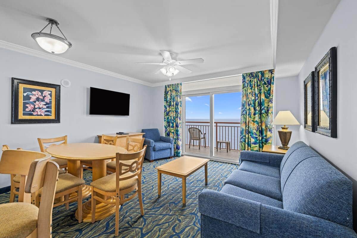 Living area of an oceanfront condo at Paradise Resort, with a dining table and doors onto the balcony