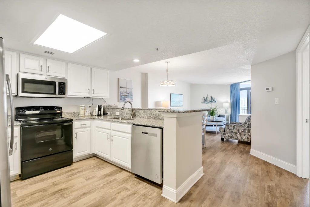 Condo kitchen at Sand Dunes Resort with granite counters, a breakfast bar and the living area beyond