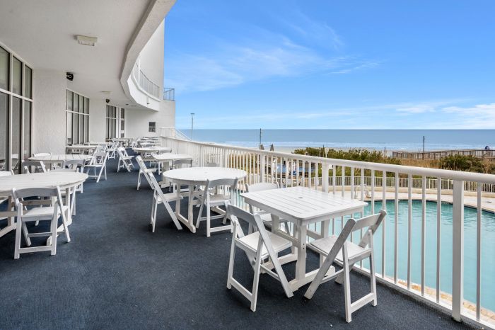 Tables on the oceanfront terrace at Sea Watch Resort, above the pool and looking out to the water