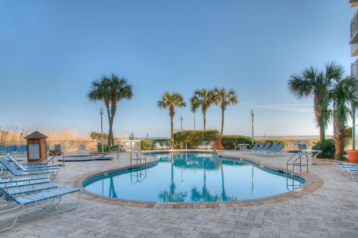 The outdoor pool ringed with palms at Sea Watch Resort, with the beach beyond