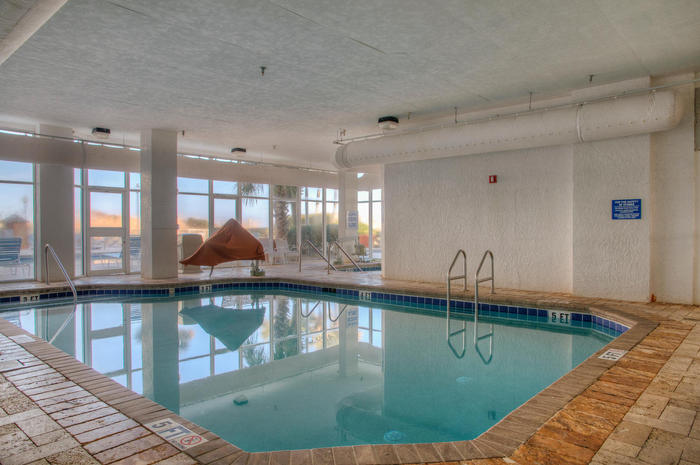 The indoor pool under tall windows at Sea Watch Resort